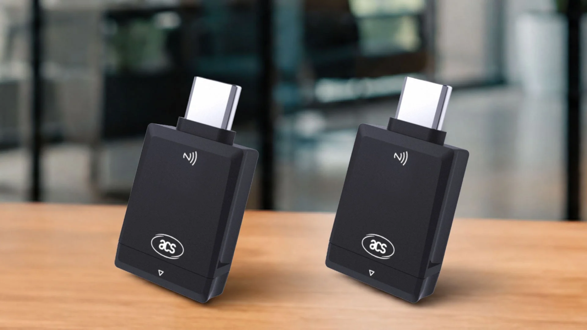 木製のテーブルに置かれた2つの黒いUSB-C非接触型リーダー（ドングル）。NFC/RFIDシンボルと「acs」ロゴが特徴です。
