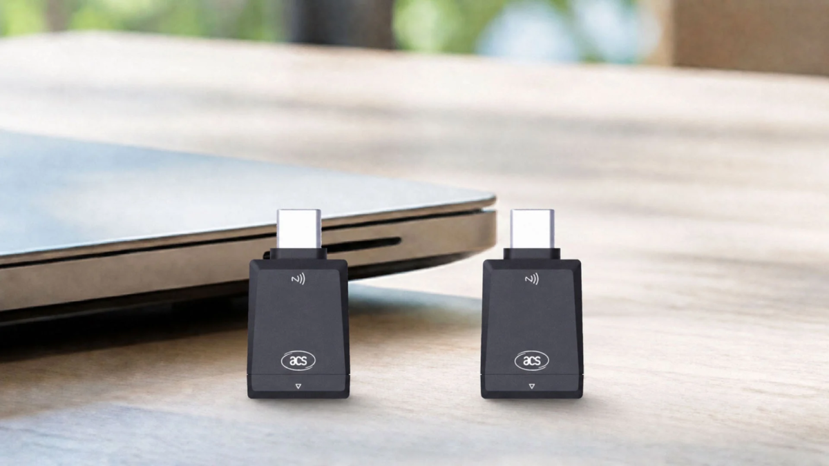 2つの黒いUSB-Cワイヤレスアダプターが、ノートパソコンの隣の木製テーブルに置かれています。