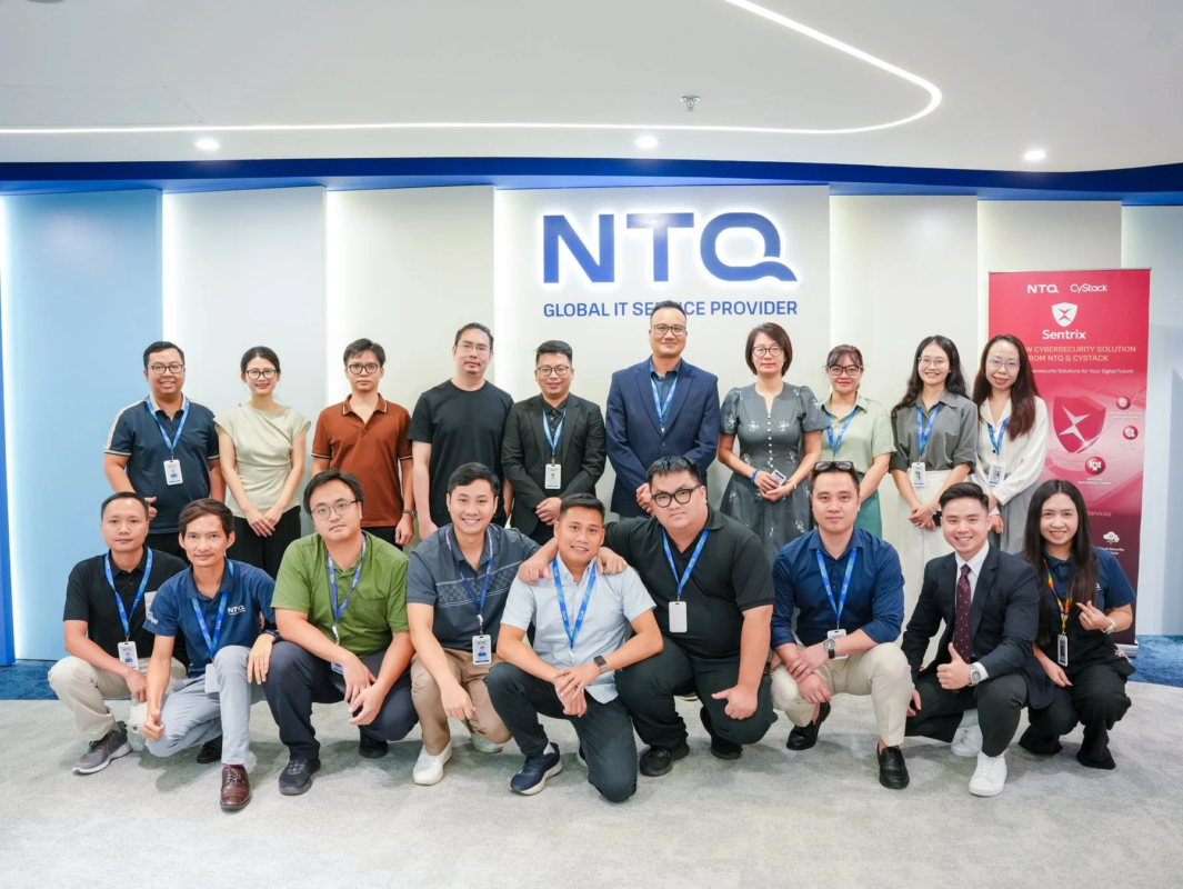 現代的なオフィス環境で、NTQ社の社員が集合写真を撮影している様子